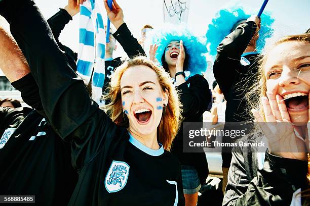 fans in team uniforms cheering during soccer match - fan women stock-fotos und bilder