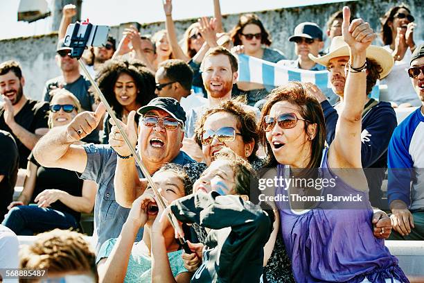 cheering family at soccer match using selfie stick - fußball fan oma stock-fotos und bilder