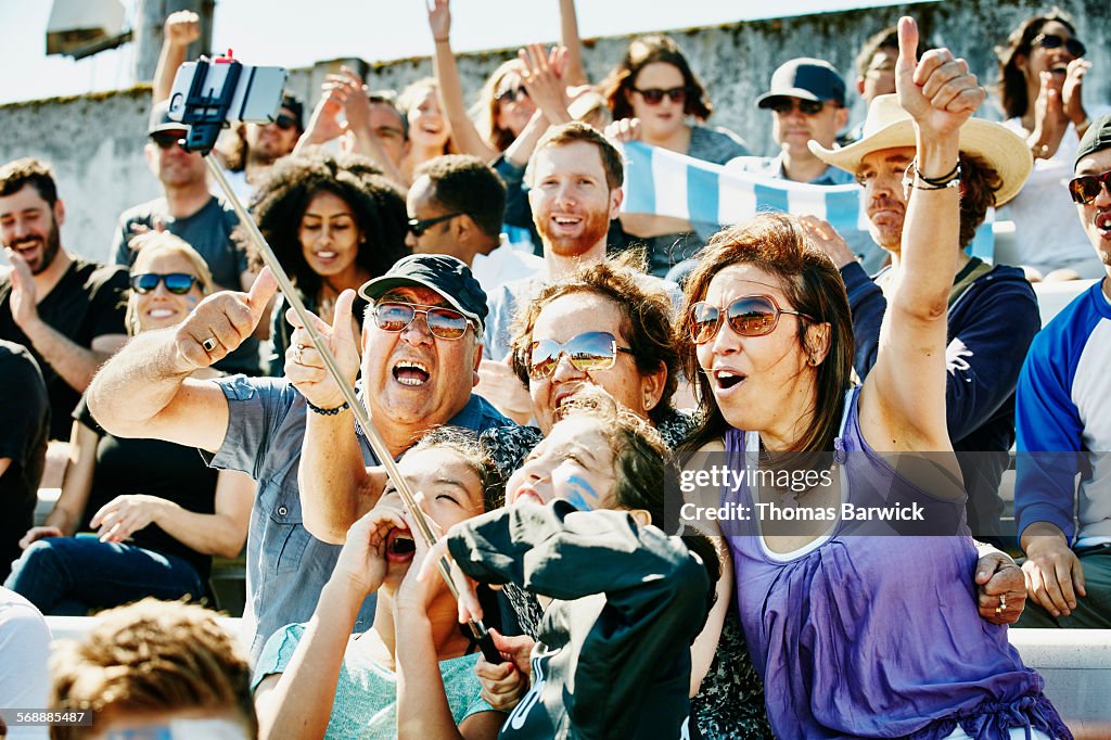 Cheering family at soccer match using selfie stick