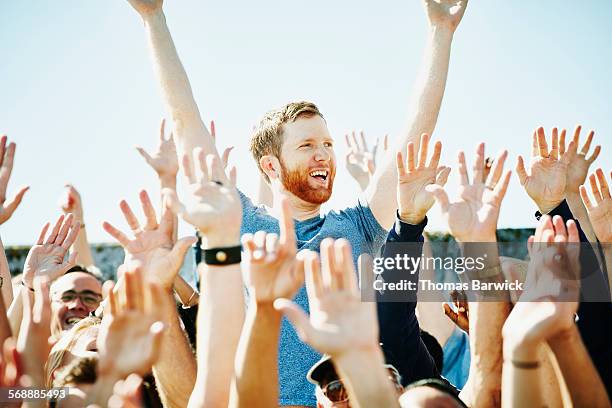 man cheering in crowd with arms raised - cheering crowd stockfoto's en -beelden