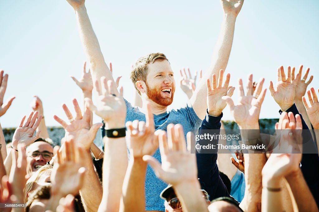 Man cheering in crowd with arms raised