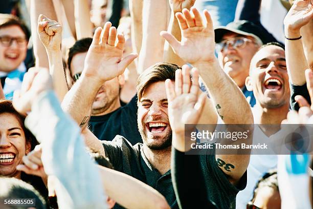 laughing man cheering with crowd in stadium - voetbalcompetitie sportevenement stockfoto's en -beelden