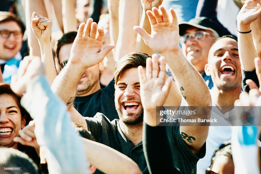 Laughing man cheering with crowd in stadium