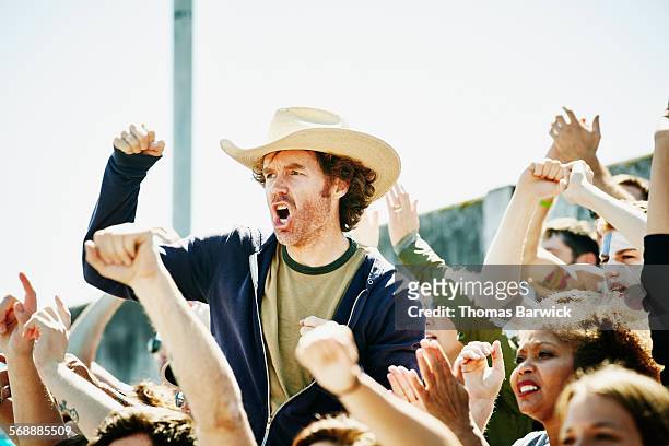 cheering man standing in crowd during soccer match - american football sport fotografías e imágenes de stock