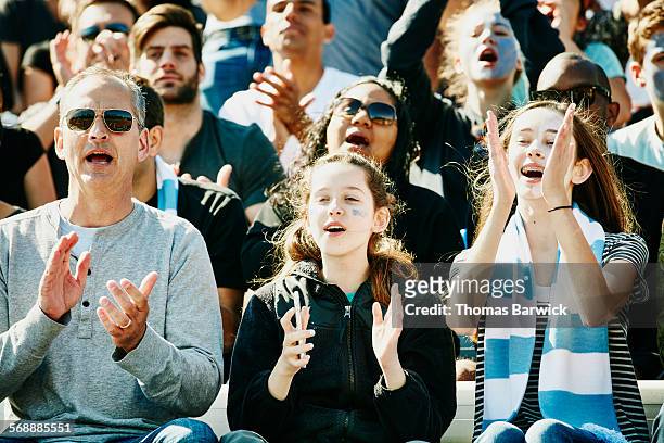 father and daughters cheering at soccer match - voetbalcompetitie sportevenement stockfoto's en -beelden