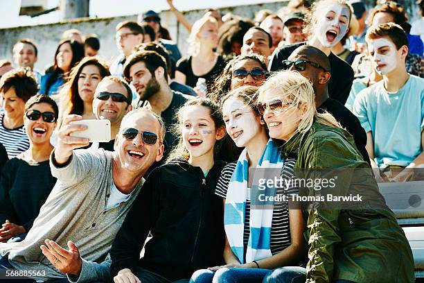 laughing family at soccer match taking selfie - avvenimento sportivo foto e immagini stock