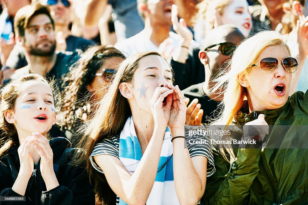 Mother and daughters cheering during soccer match