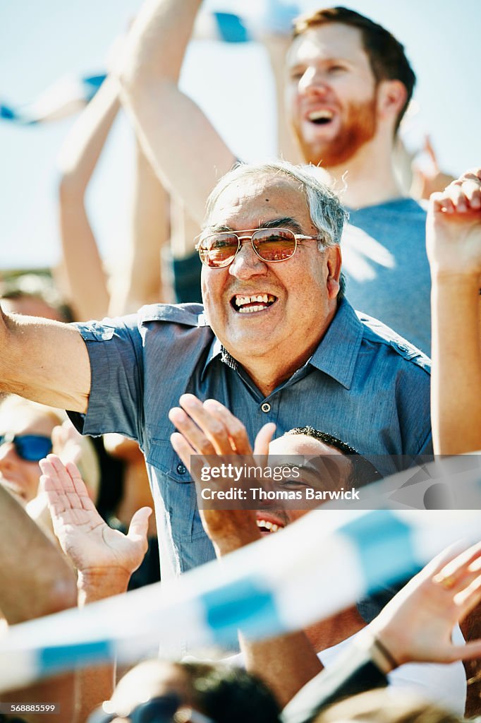 Senior man cheering in crowd during soccer match