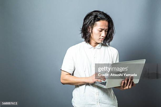 portrait of asian man using laptop - laptop studio shot stock pictures, royalty-free photos & images