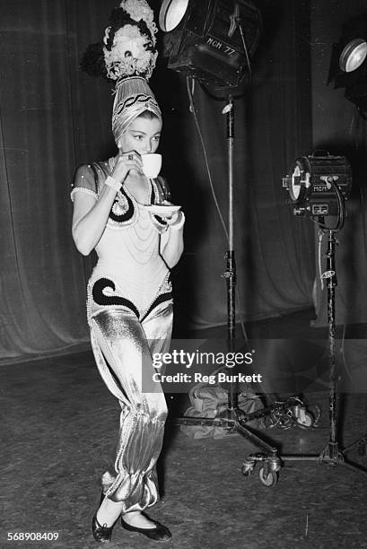 Actress Gene Tierney drinking a cup of tea in costume, during a break in filming the Scheherazade Ballet scene for the film 'Never Let Me Go' at...