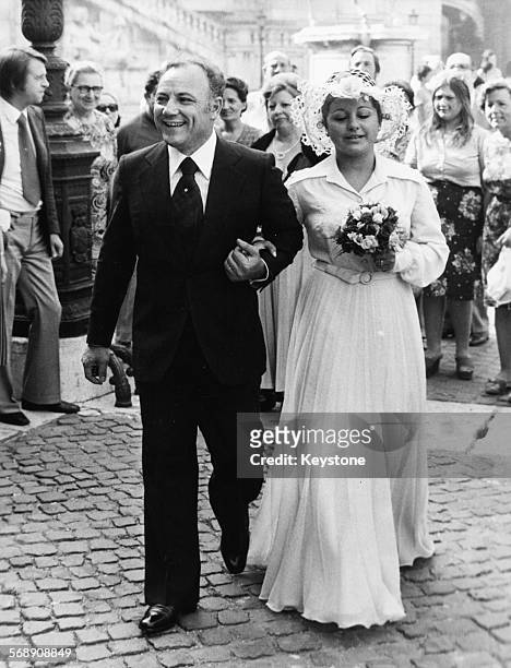 Singer Claudio Villa and his new wife Patrizia Baldi walking past crowds of people as they leave the church following their wedding, 1970.
