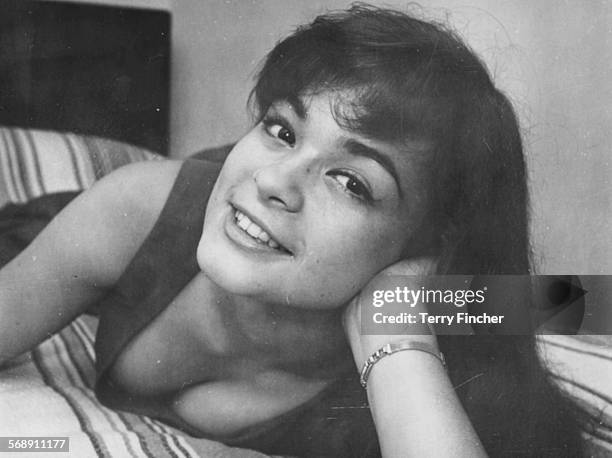 Portrait of actress Marie Versini reclining on a bed prior to attending a reception held in her honor as she films 'The Tale of Two Cities', at the...