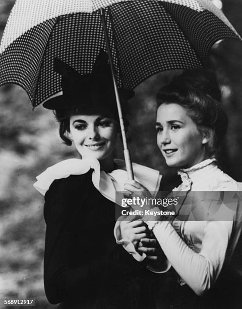 Actresses Juliette Villard and Brigitte Fossey sharing an umbrella on the set of the film 'Le Grand Meaulnes', circa 1967.