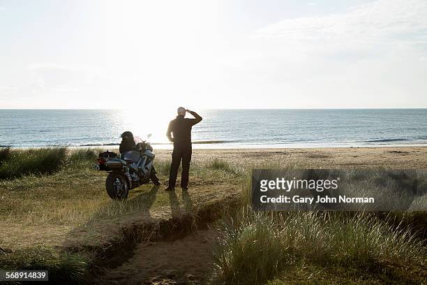 mature male motorcyclist enjoys view after a ride. - mare moto foto e immagini stock