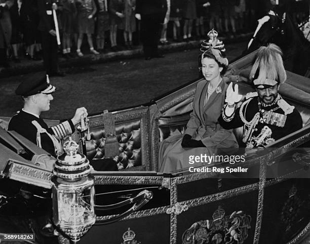 Emperor Haile Selassie waving as he rides in an open Landau carriage with Queen Elizabeth II and Prince Philip, the Duke of Edinburgh, during a state...