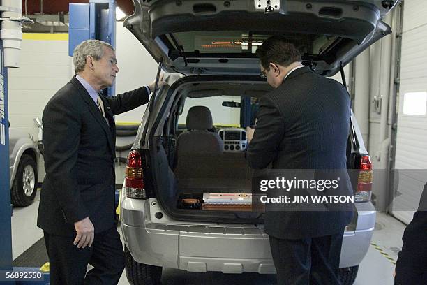 Glendale, UNITED STATES: US President George W. Bush looks over a lithium hybrid battery installed in a new Ford Escape as Mike Andrew conducts a...