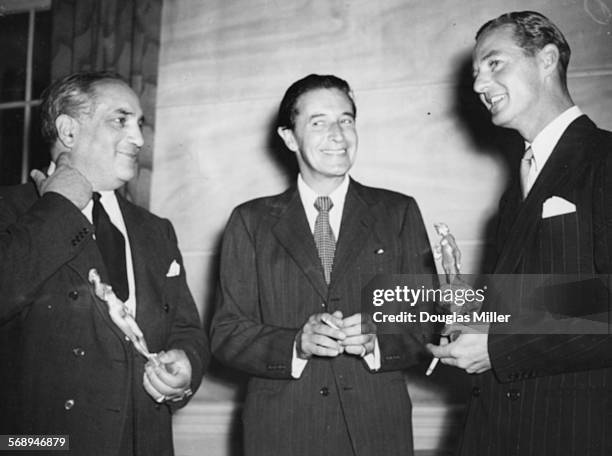 Playwright Terence Rattigan holding his award, with fellow award winner Frederick Valk and Chairman of the Committee Ivor Novello, at the Theatre...