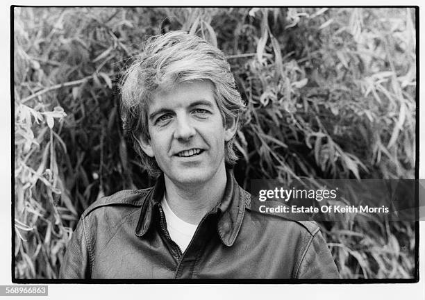 Outdoor portrait of musician Nick Lowe wearing a leather jacket, circa 1990.