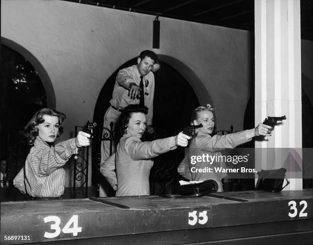 American actress Ann Robinson learns to shoot in the proper fashion from real policewomen Pat Wright and June Howard as shooting instructor Sergeant...