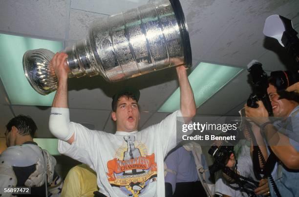 Canadian hockey player Mark Recchi of the Pittsburgh Penguins hoists the Stanley Cup over his head as he celebrates in the dressing room after their...