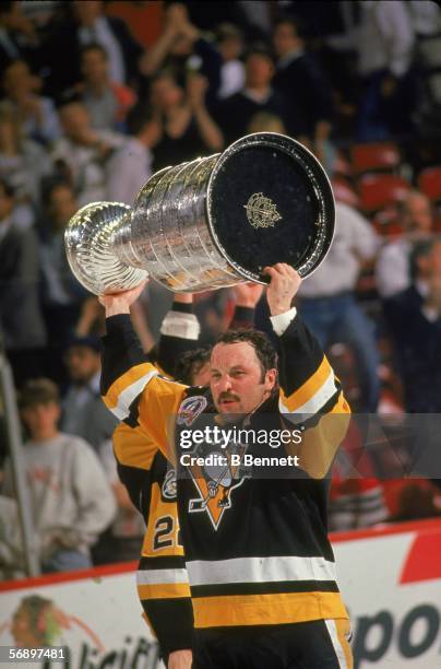 Canadian hockey player Bryan Trottier of the Pittsburgh Penguins raises the Stanley Cup over his head in celebration of their championship victory...