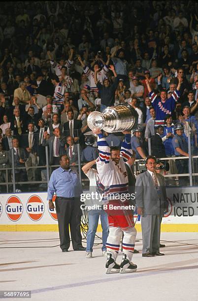 Canadian professional hockey player Glenn Anderson of the New York Rangers hoists the Stanley Cup over his head as he celebrates their championship...