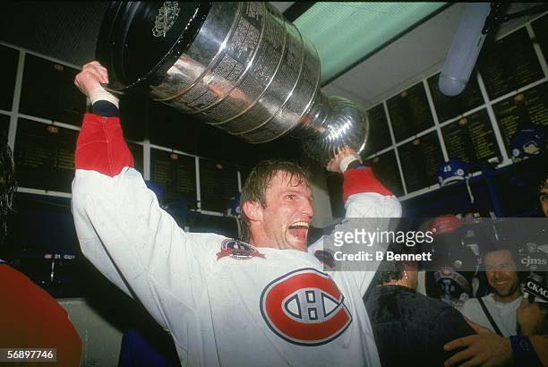 Canadian professional hockey player Kirk Muller of the Montreal Canadiens hoists the Stanley Cup over his head as he celebrates their championship...