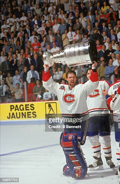 Canadian professional hockey player Patrick Roy of the Montreal Canadiens hoists the Stanley Cup over his head as he celebrates their championship...