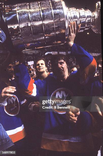 Canadian professional hockey player Mike Bossy of the New York Islanders hoists the Stanley Cup over his head as he celebrates their championship...