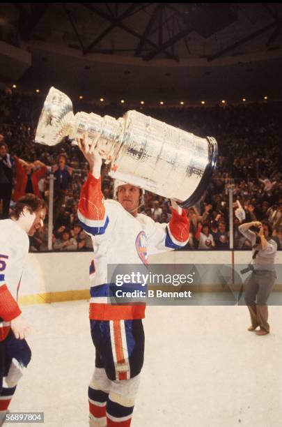 Canadian professional hockey player Mike Bossy of the New York Islanders hoists the Stanley Cup over his head as he celebrates their championship...