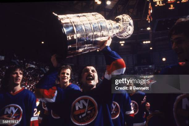 Canadian professional hockey player Bryan Trottier of the New York Islanders hoists the Stanley Cup over his head as he celebrates their championship...