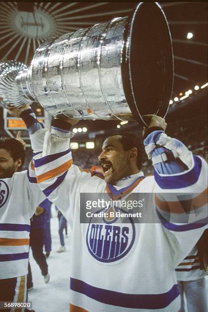 Canadian professional hockey player Grant Fuhr of the Edmonton Oilers hoists the Stanley Cup over his head as he celebrates their championship...