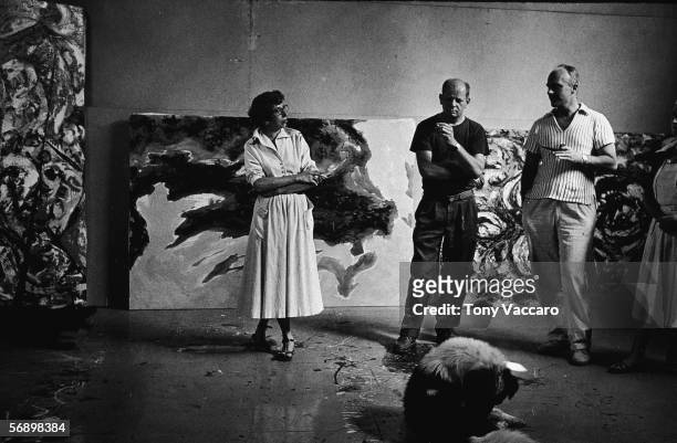 American abstract expressionist painter Jackson Pollock and his wife Lee Krasner and an unidentified couple stand around a dog and smoke in his...