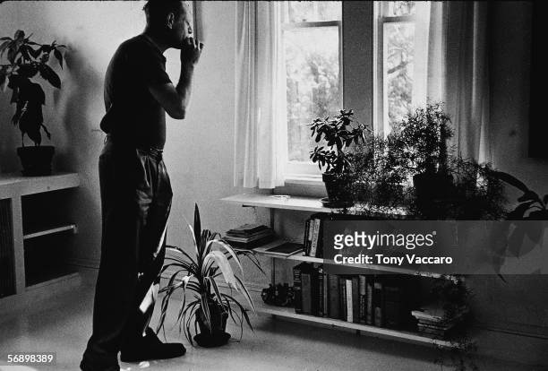 American abstract expressionist painter Jackson Pollock smokes a cigarette as he looks out a window of 'The Springs,' East Hampton, New York, August...