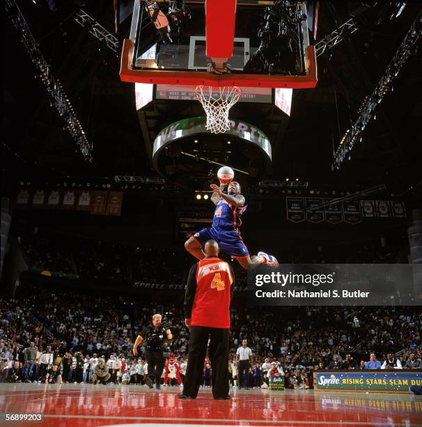 Nate Robinson of the New York Knicks completes a dunk as he jumps over former slam dunk champion Spud Webb during the Sprite Rising Stars Slam Dunk...