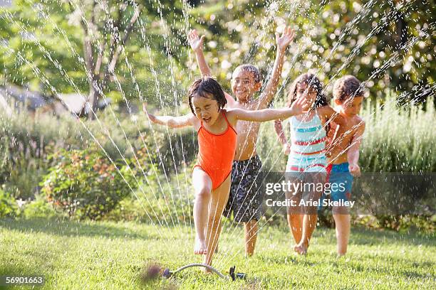 children running through water sprinkler - girl running stock pictures, royalty-free photos & images