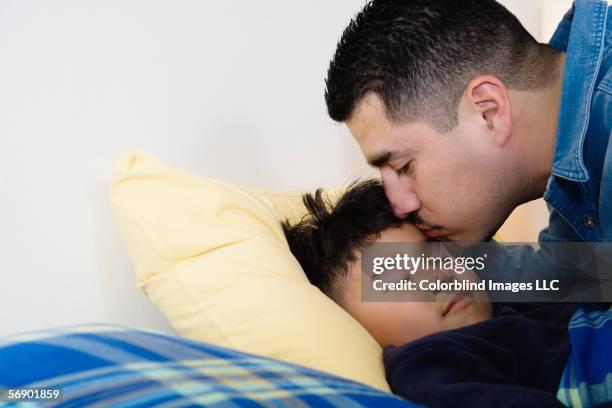 father kissing son on forehead - good night kiss stock-fotos und bilder