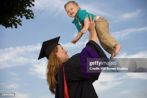 Young Female Graduate Holding Boy High-Res Stock Photo