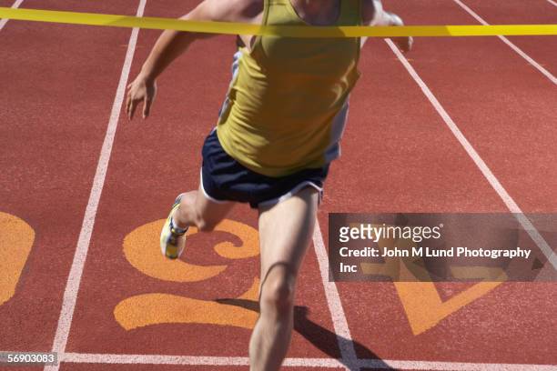 male runner crossing the finish line - finish line ribbon stock pictures, royalty-free photos & images