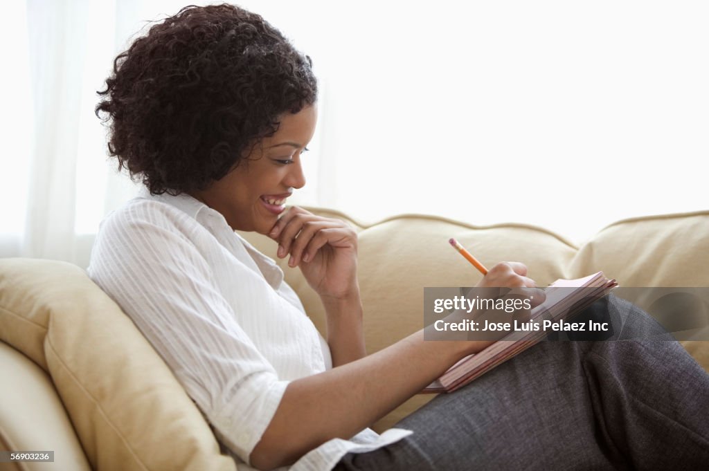 Woman sitting on sofa with notepad on her lap