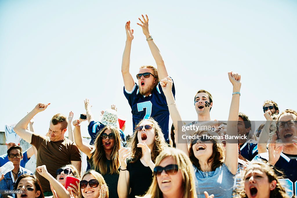 Fan jumping above celebrating crowd in stadium