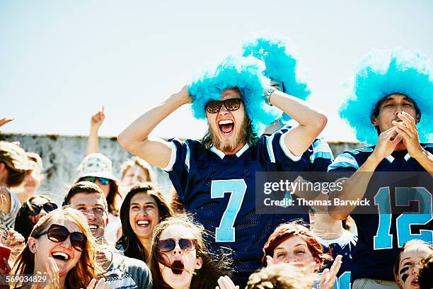 fans cheering after team scores touchdown - woman in sports jersey stock pictures, royalty-free photos & images