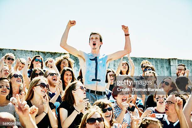 painted football fan cheering in crowd in stadium - sin camisa fotografías e imágenes de stock