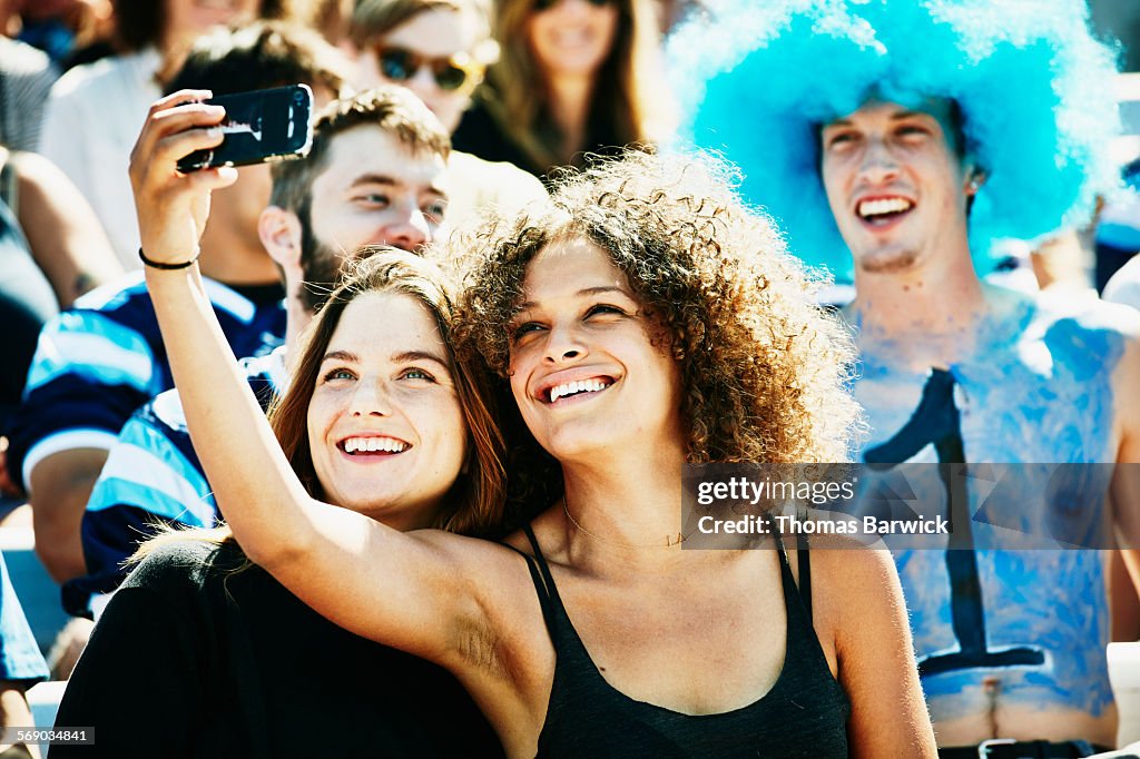 Friends at football game in stadium taking selfie