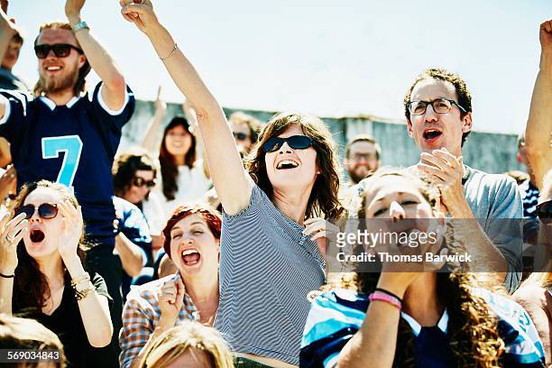 crowd of football fans cheering in stadium - football américain femme photos et images de collection