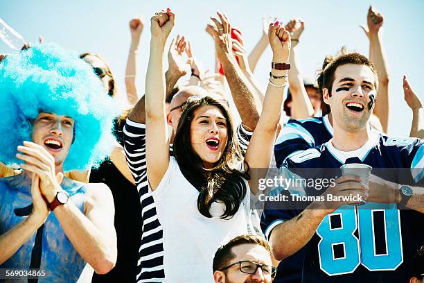 football fans in stadium celebrating touchdown - football américain femme photos et images de collection