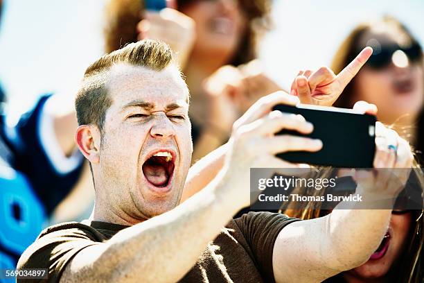 man celebrating at football game taking selfie - boomwa stock pictures, royalty-free photos & images