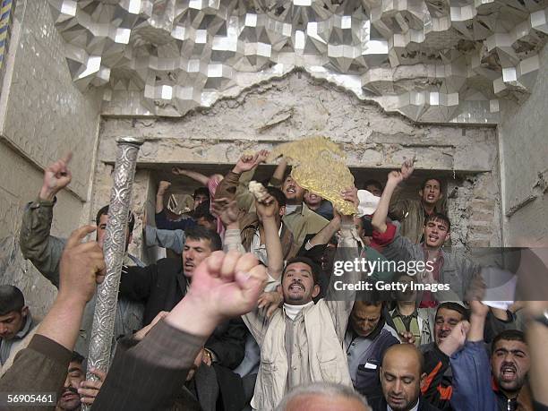 Angry protesters shout slogans as one of them holds a golden piece of debris retrieved from inside the Shiite holy shrine of Ali al-Hadi on February...