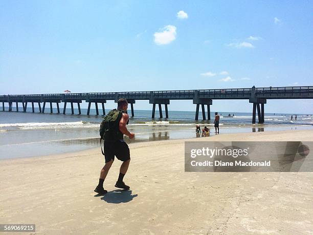 One man with a backpack jogging on the beach at Jacksonville Beach, Florida, USA on July 22, 2015.