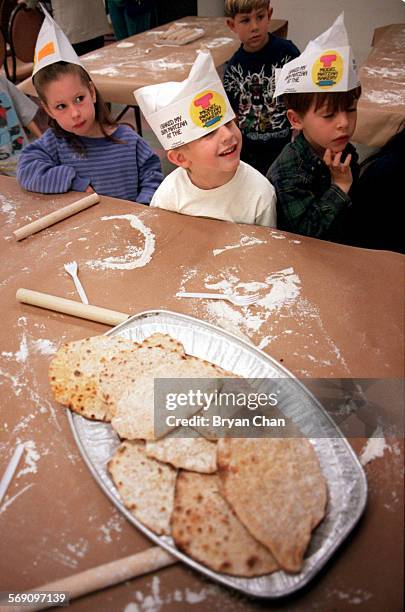 Fouryearolds Jamie Lebowitz, lr, Trevor Paperny and Ben Idan patiently wait to try the Matzo bread, foreground, they made at the Chabad of...